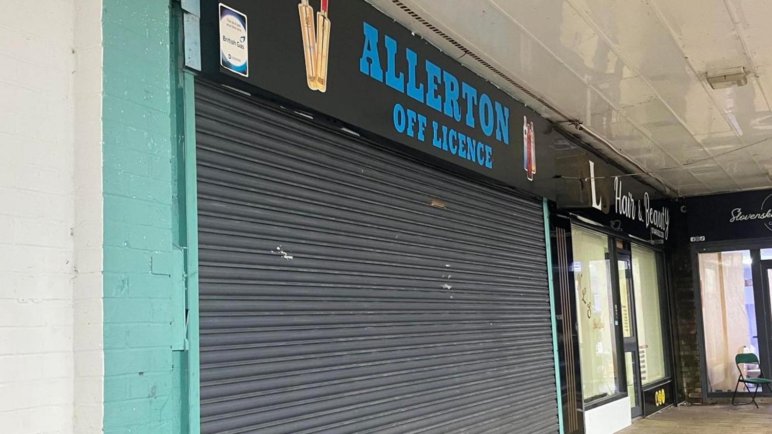 A shop with its black shutters pulled down, indicating it is closed.
