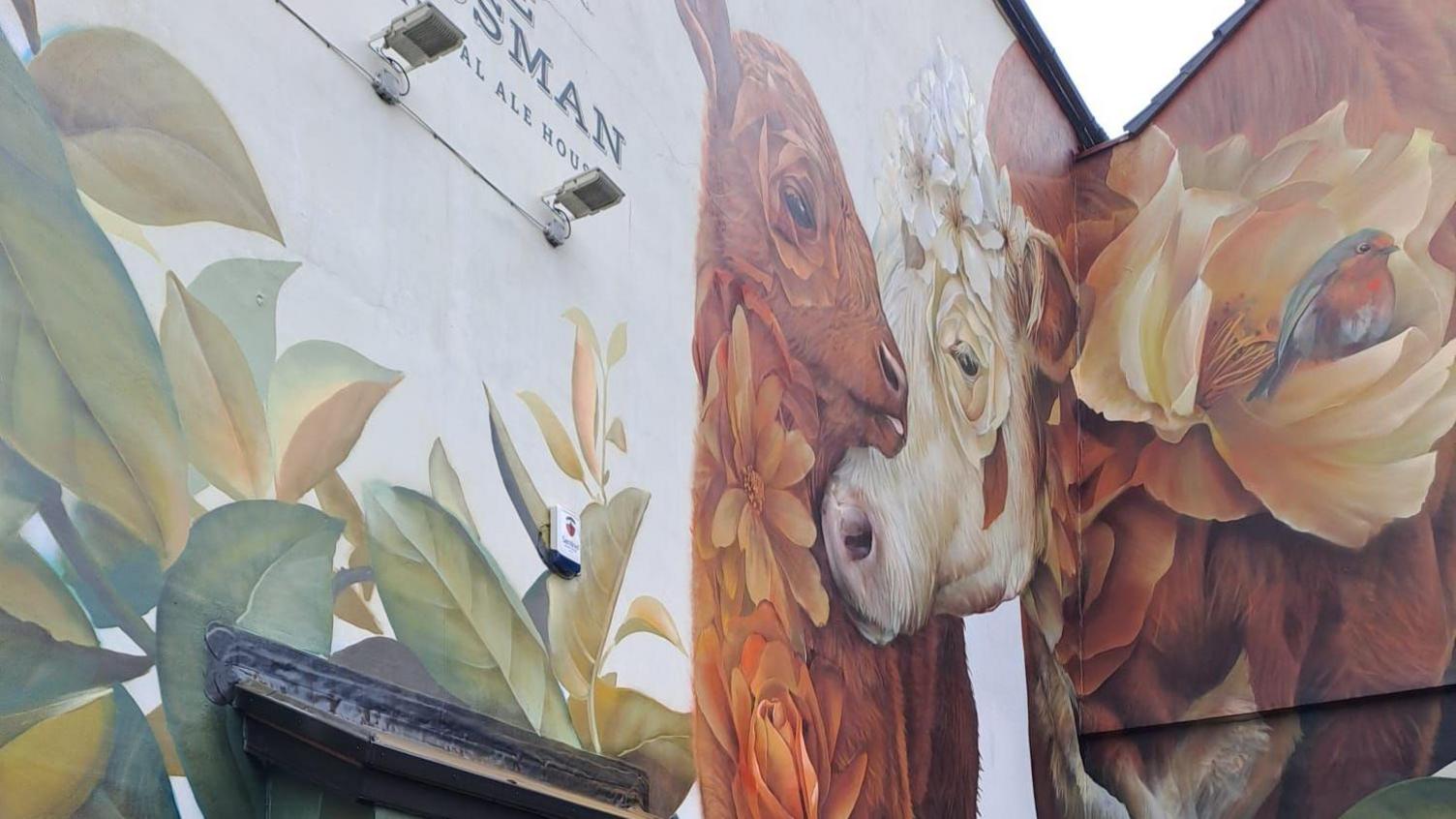 Mural depicting two cows on the side of a building