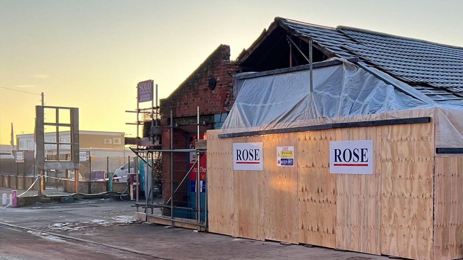 A damaged building with protective boarding around it.