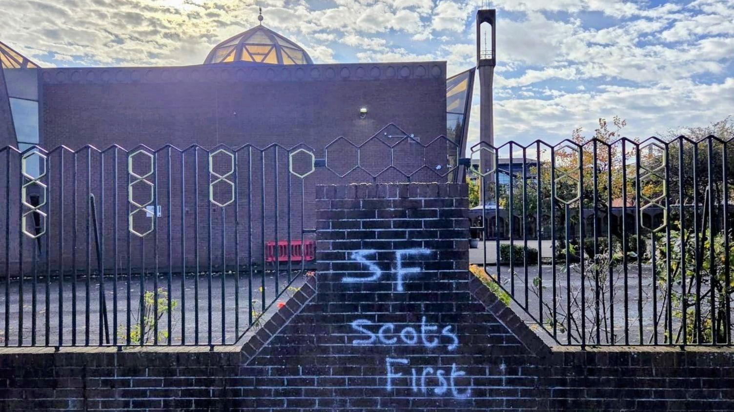 A mosque building, with graffiti saying Scots First written on a wall next to it.