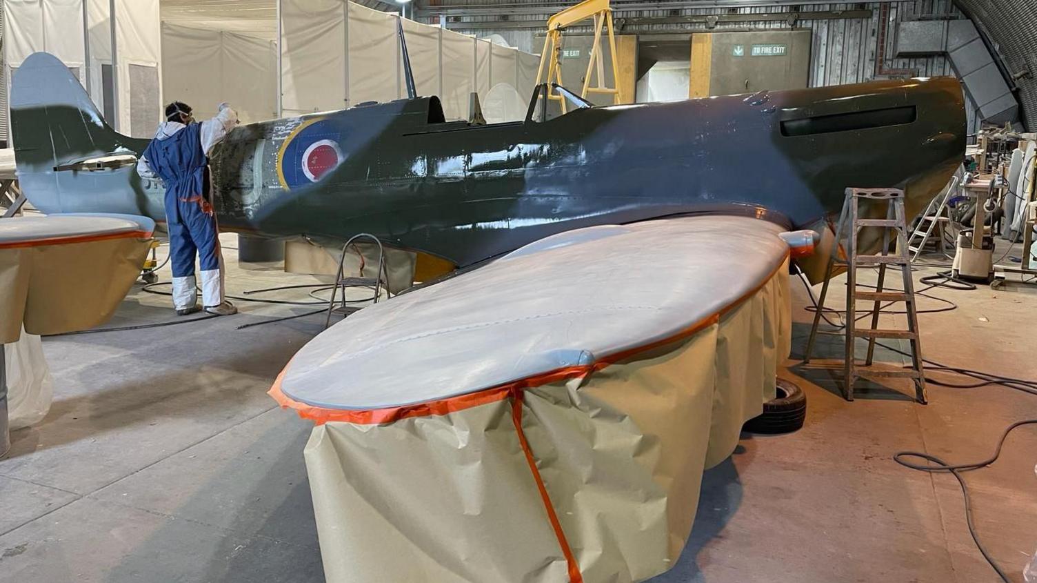 The interior view of a warehouse where a replica spitfire is being painted 