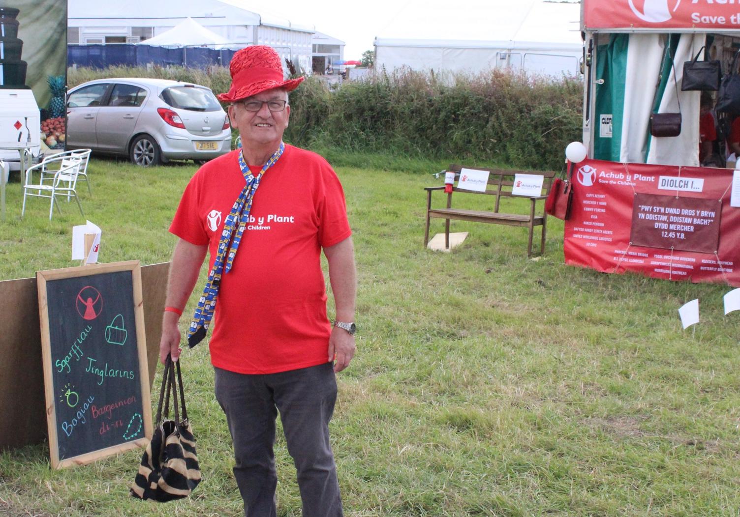 Dyma sy'n digwydd pan mae Achub y Plant yn cynnal arwerthiant o hen fagiau a hetiau i godi arian! // Luckily for this volunteer there's no dress code at the Eisteddfod