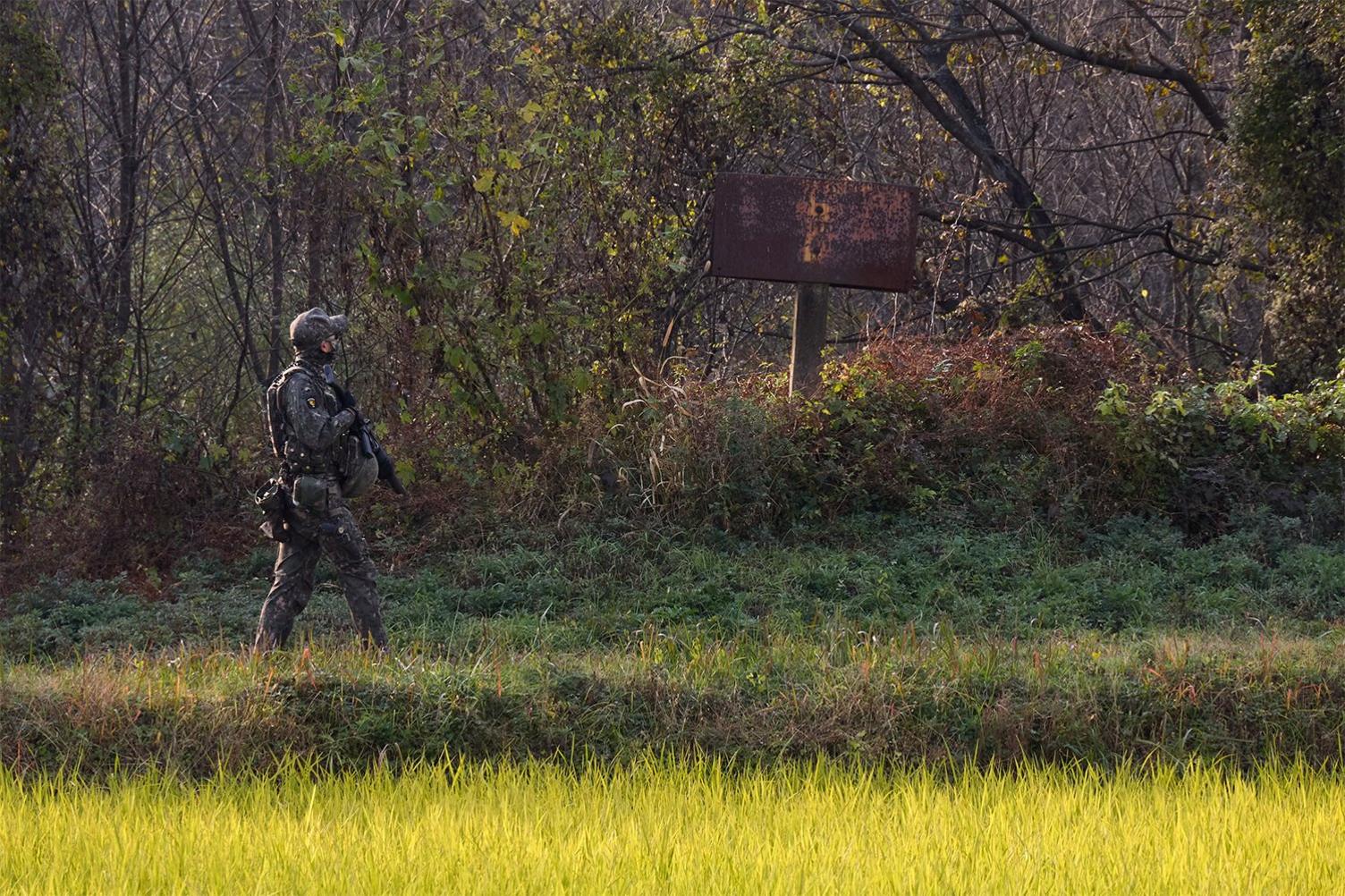 Soldier walk near the sign that marks the border