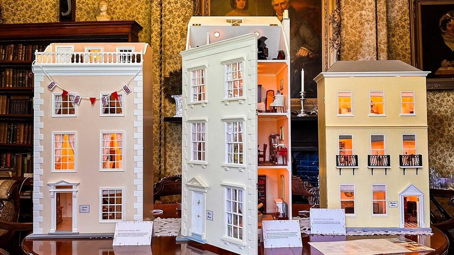 Three delicate three storey dolls houses placed on a table in the Grove Museum.