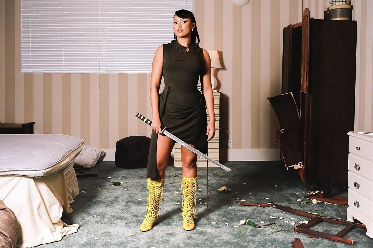 Joy Crookes holds a katana, amid the wreckage of a suburban bedroom, in a still image from her video I Know You'd Kill