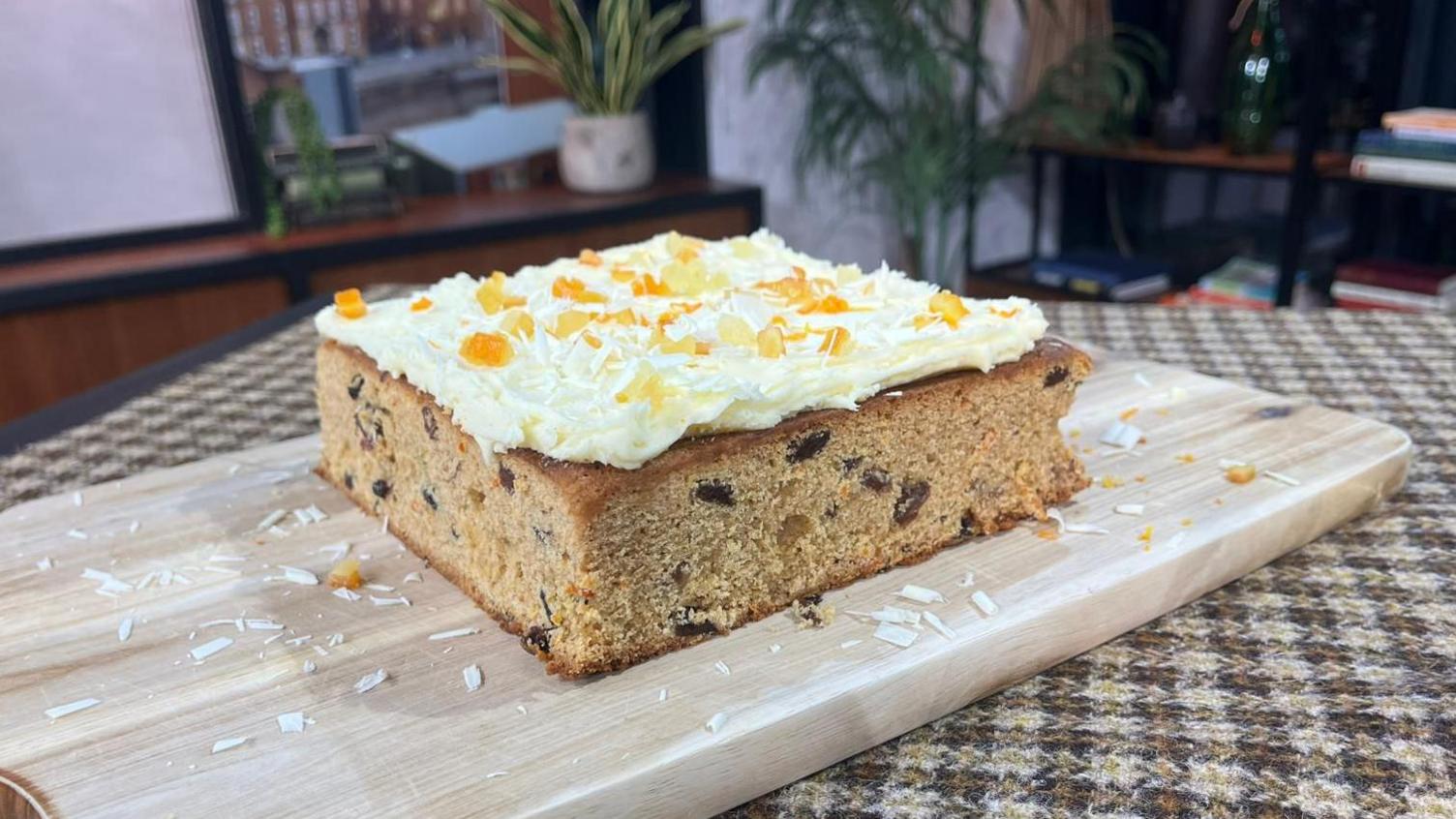 A mincemeat traybake topped with white chocolate buttercream, mixed peel and white chocolate shavings.