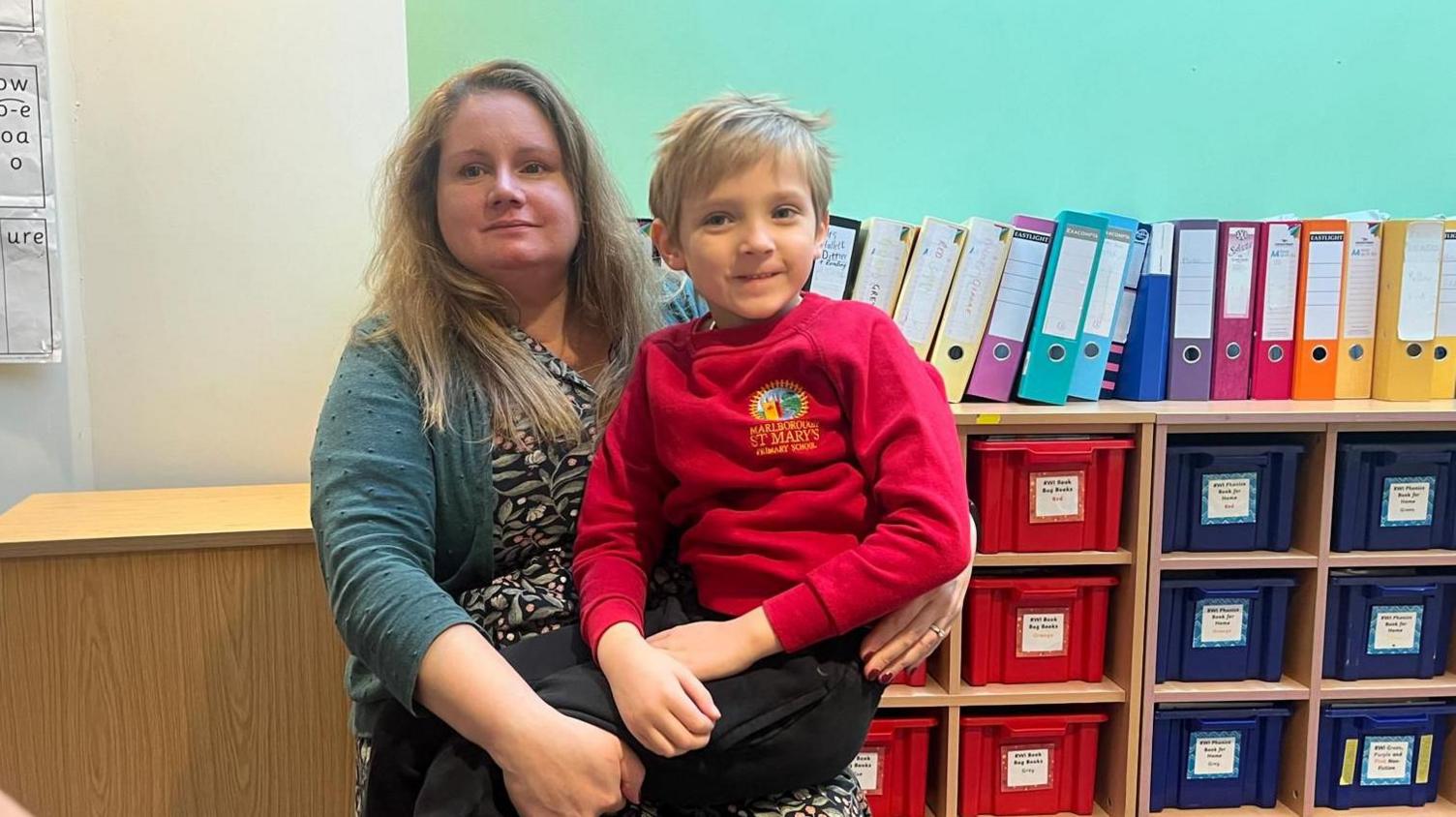 Penny and her son Thomas, sitting in a classroom. They both have blonde hair and are smiling.