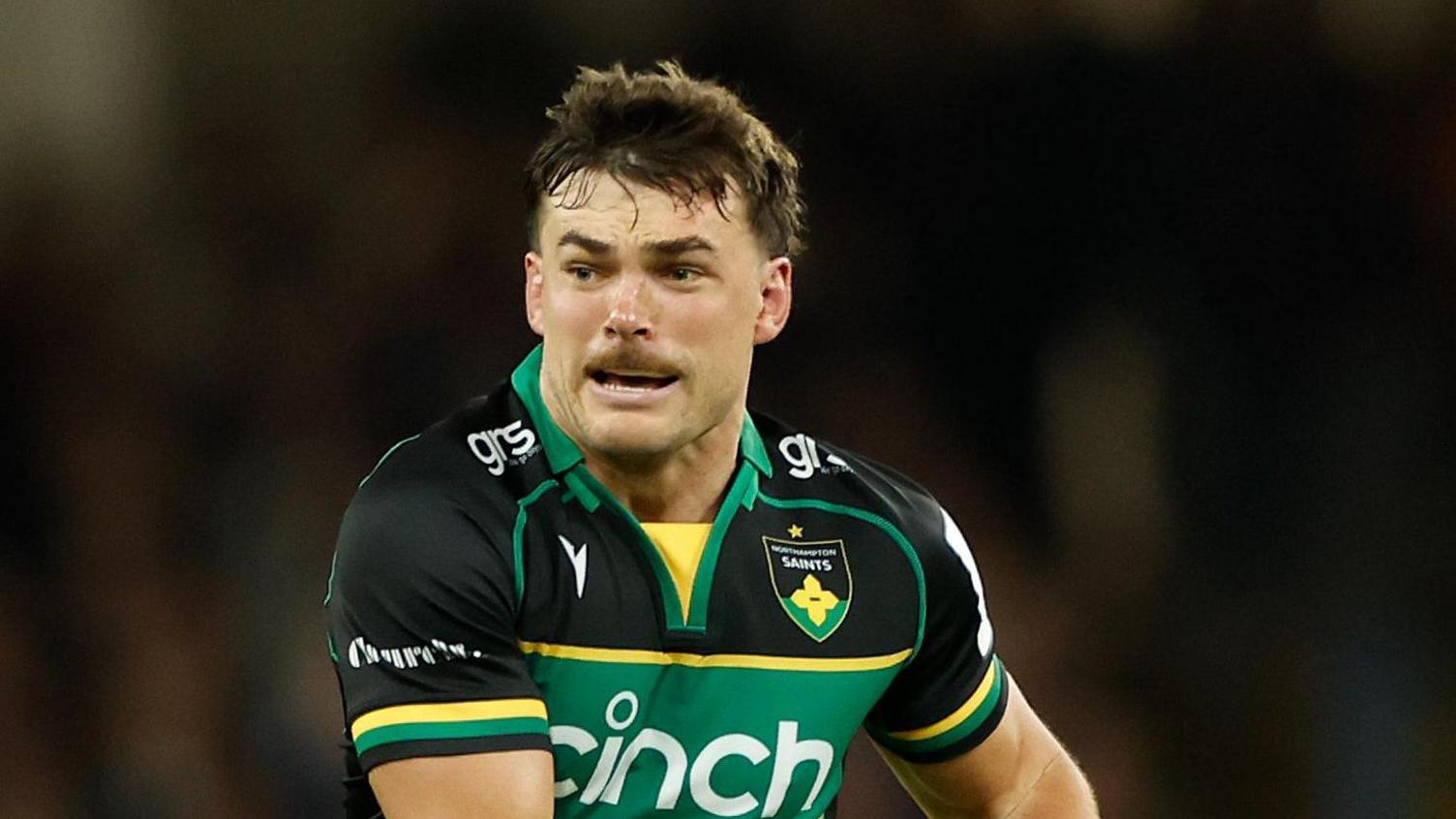 George Furbank playing for Northampton, holding the ball in two hands towards his left side, about to pass it