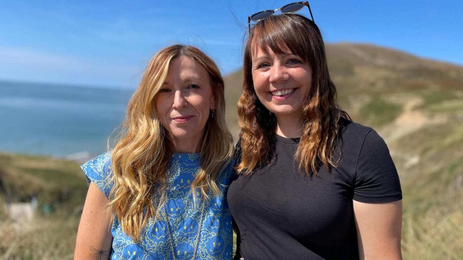 Y gantores  Non Parry a Vicky Powner yn edrych i mewn i'r camera. Mae'r ddwy yn gwenu. Mae Non yn gwisgo top glas golau ac mae Vicky yn gwisgo top lliw tywyll.  