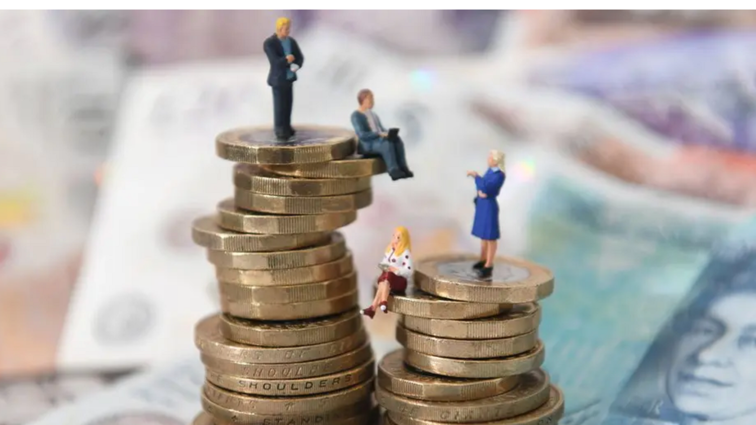 Two piles of pound and two pound coins stand on a pile of notes with men standing on the higher left-hand pile and women on the right smaller pile to indicate the gender pay gap.