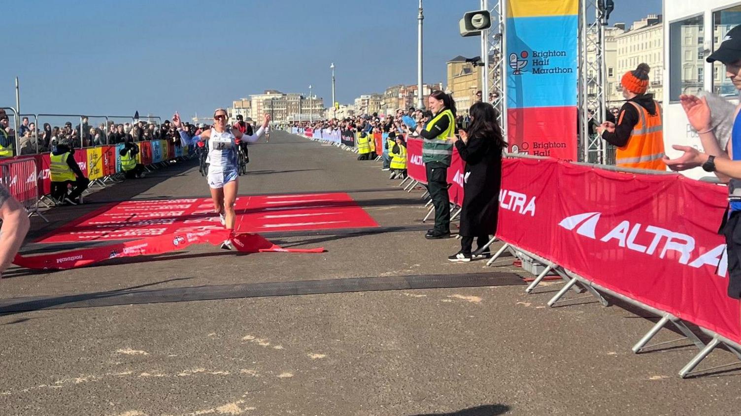 Christa Cain crossing the finishing line of the Brighton Half Marathon.