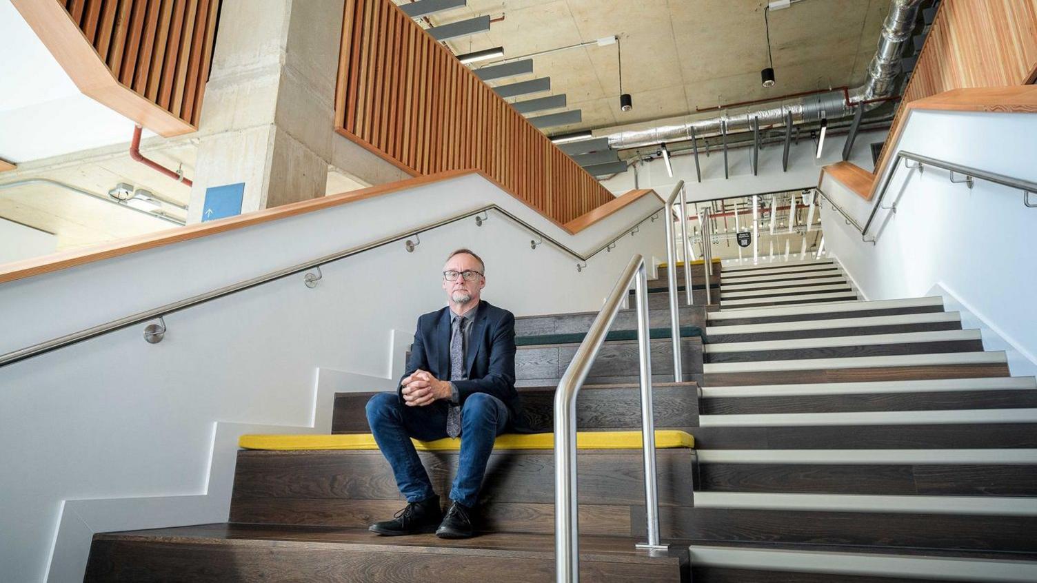 Michael Marsden, executive dean of the Nottingham School of Art & Design, sitting on a wide flight of stairs in the new building 