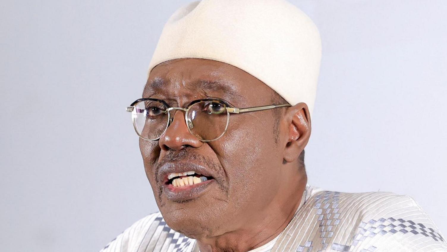 Issa Tchiroma Bakary in a white robe, glasses and white cap
