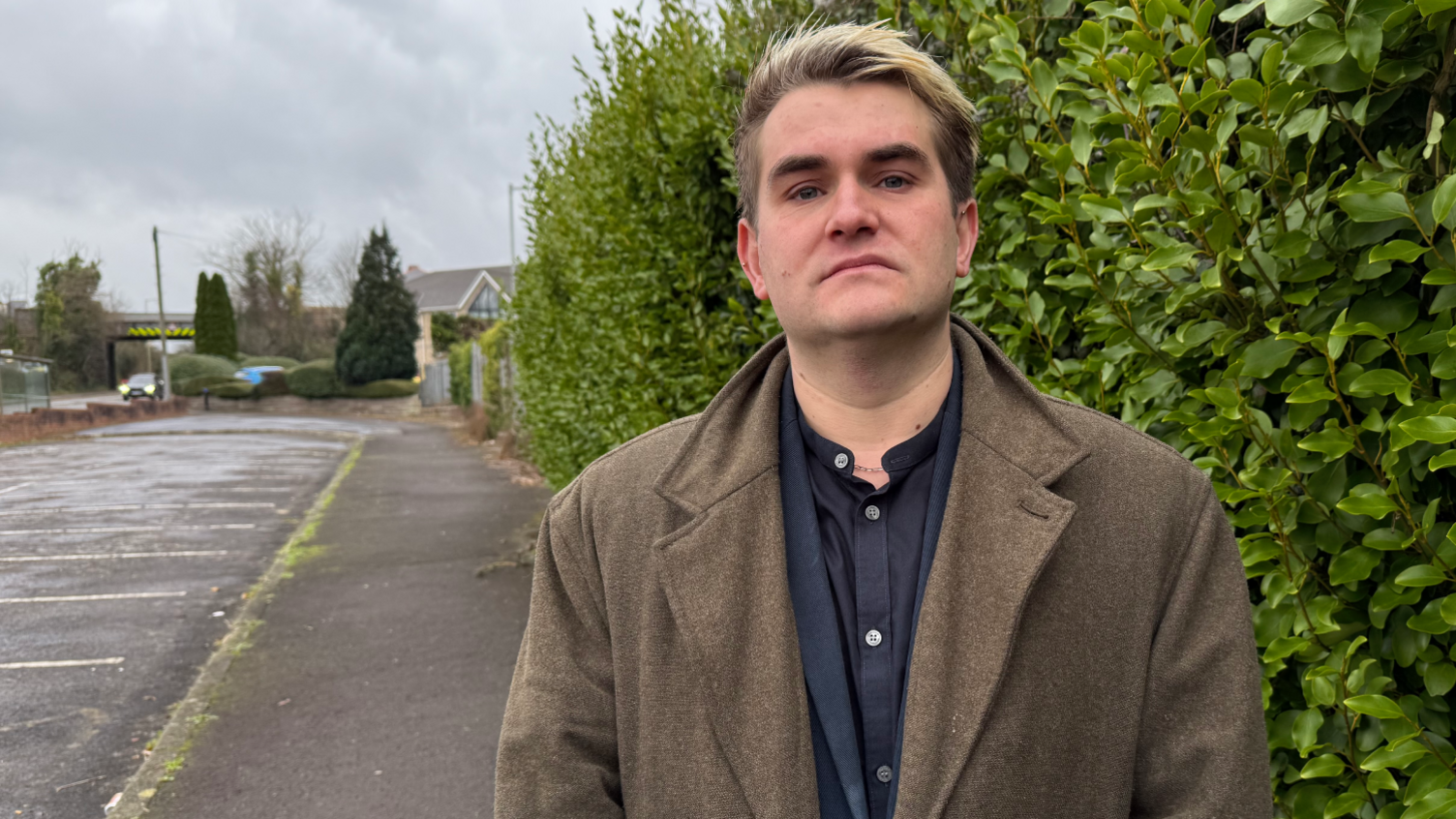 Jake Hurfurt, of Big Brother Watch, standing between a road and a hedge, looks at the camera 