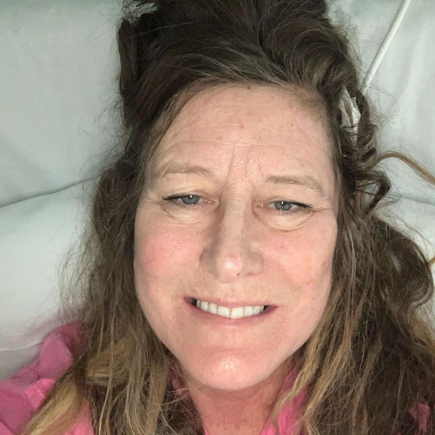 Lucy takes a selfie from above on her hospital bed, post-surgery.