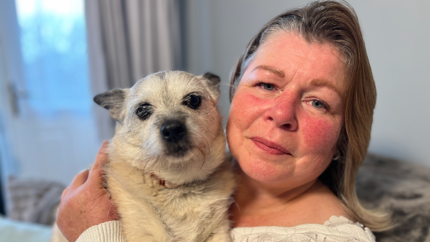 Teresa Hall mewn crys wen yn dal ci bach