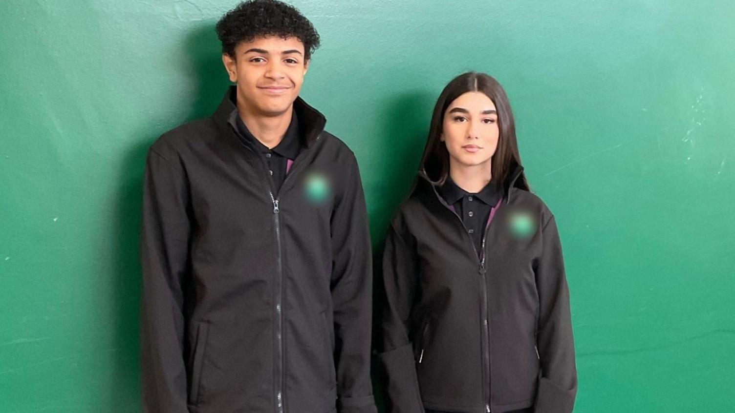 Two students seen wearing the new uniform options standing in front of a green background