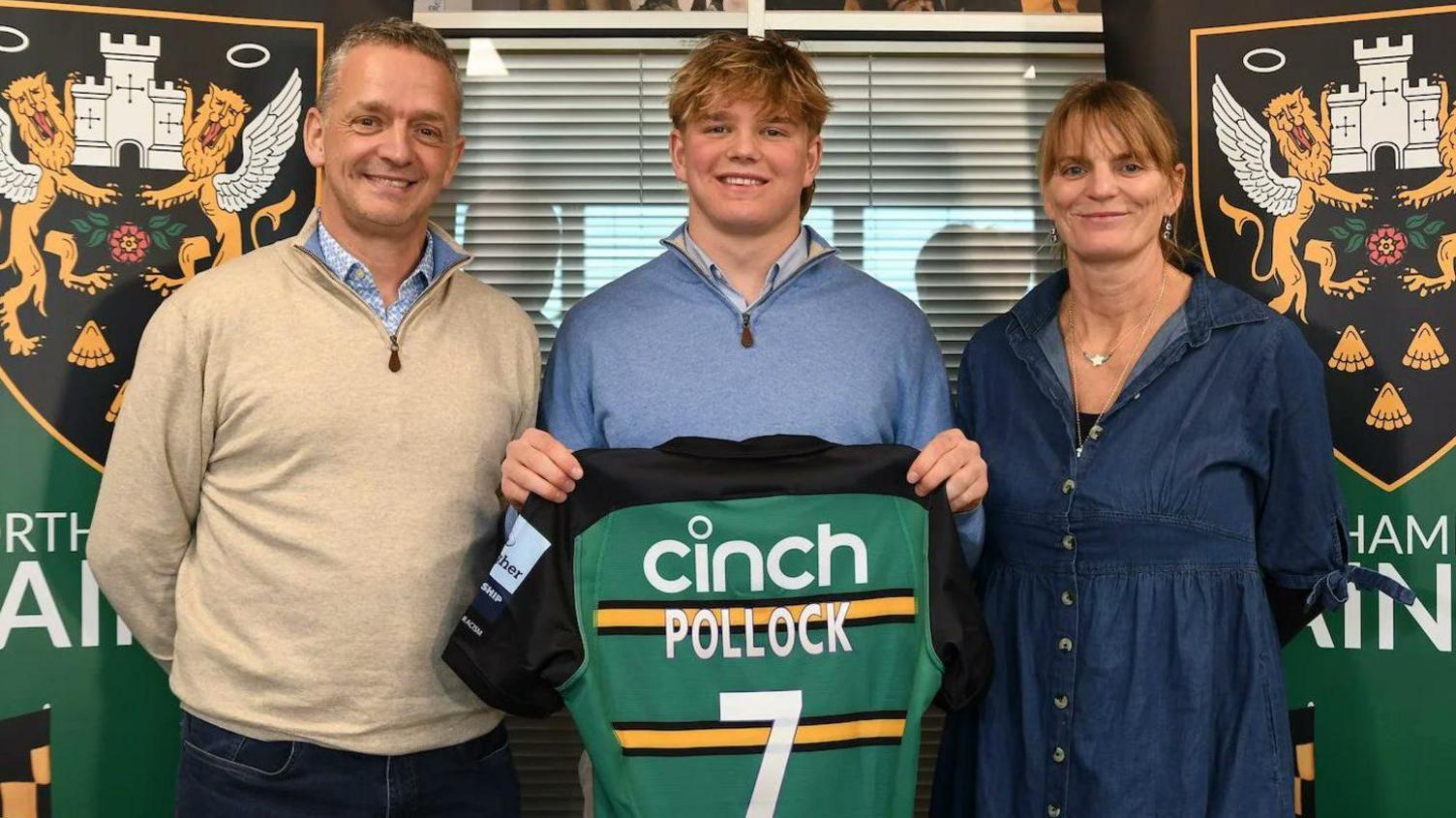 Henry Pollock standing with a Northampton Saints jersey with his parents by his side, John and Hester Pollock. 