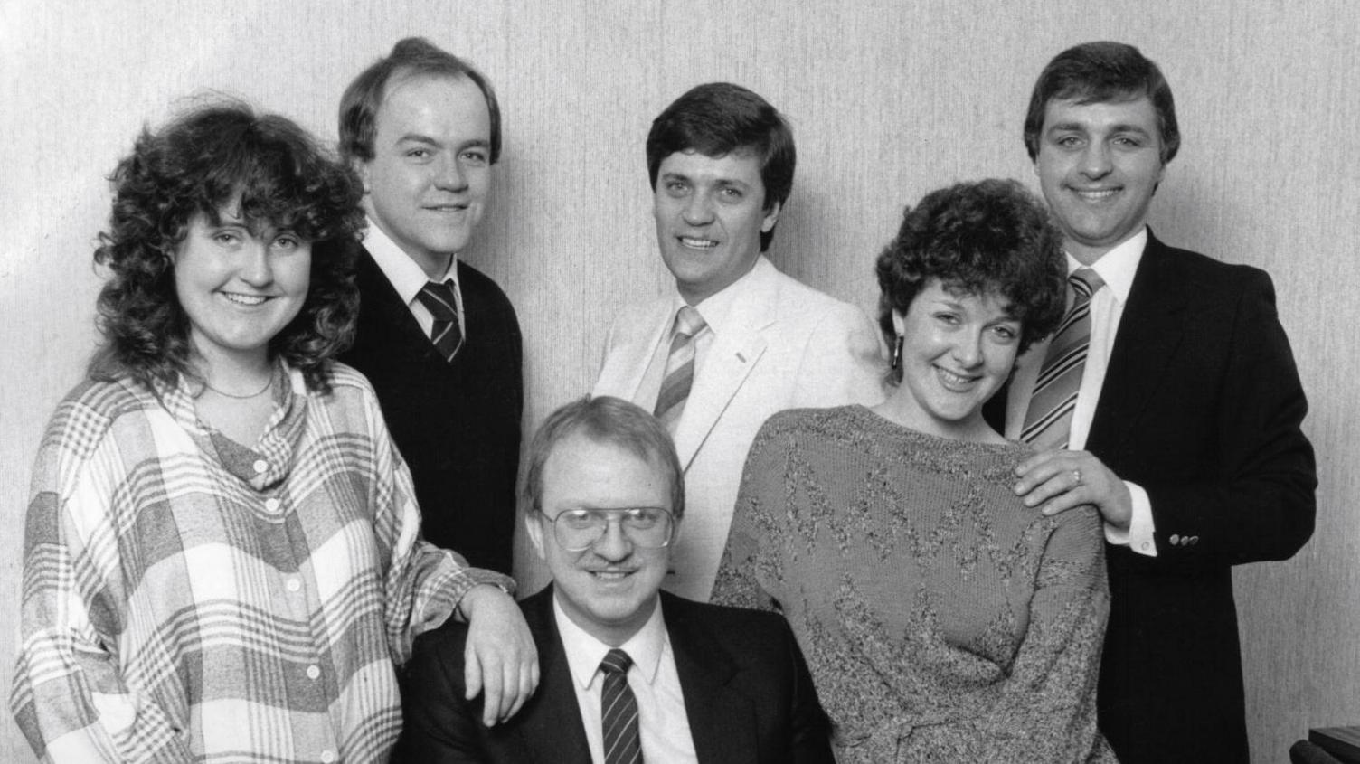 A black and white picture of the above named people. They are all dressed smartly and smiling. All are standing up except for Gavin McCoy, who is sitting.