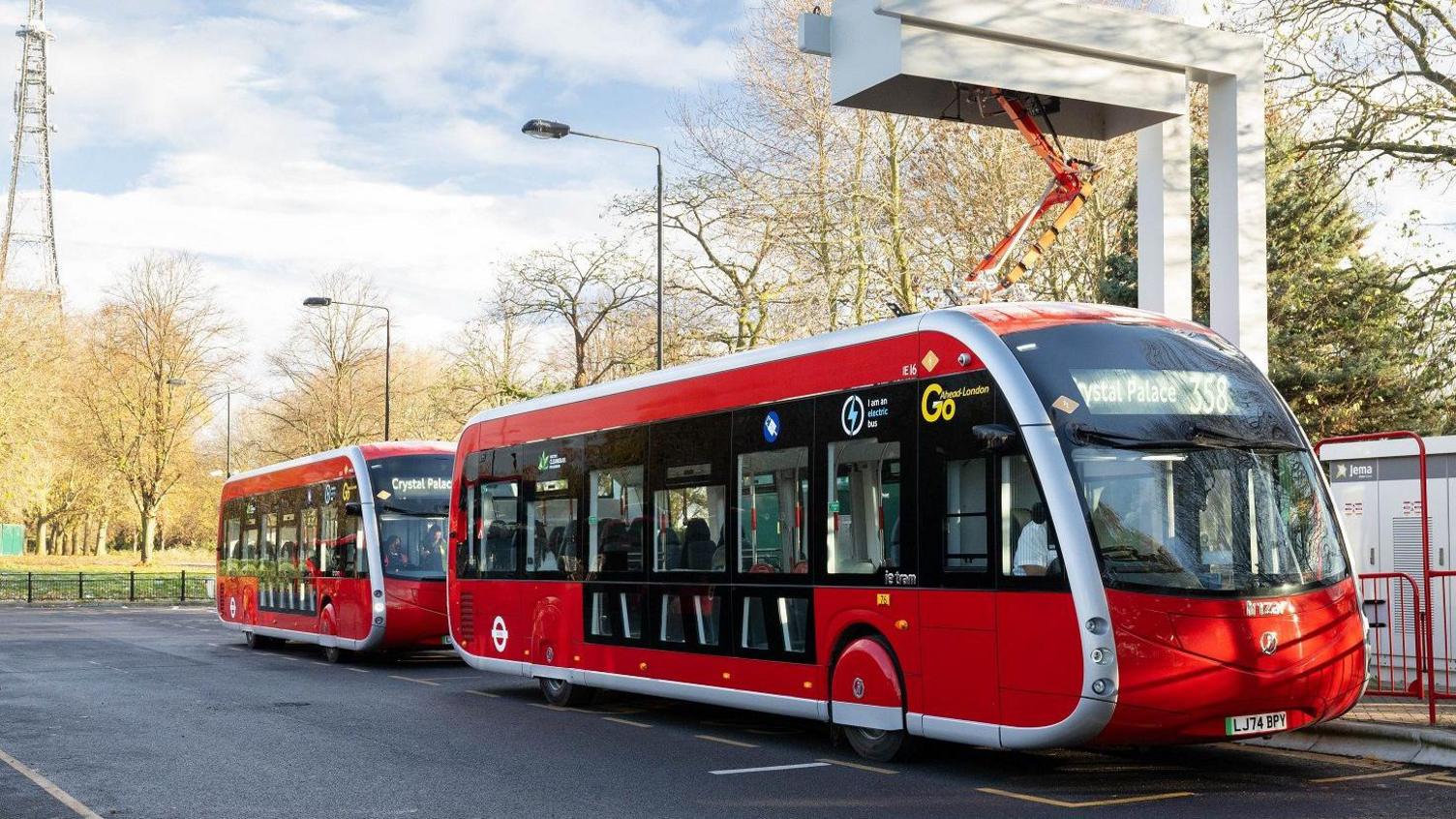 Two of the new buses charging, one in front of the other.