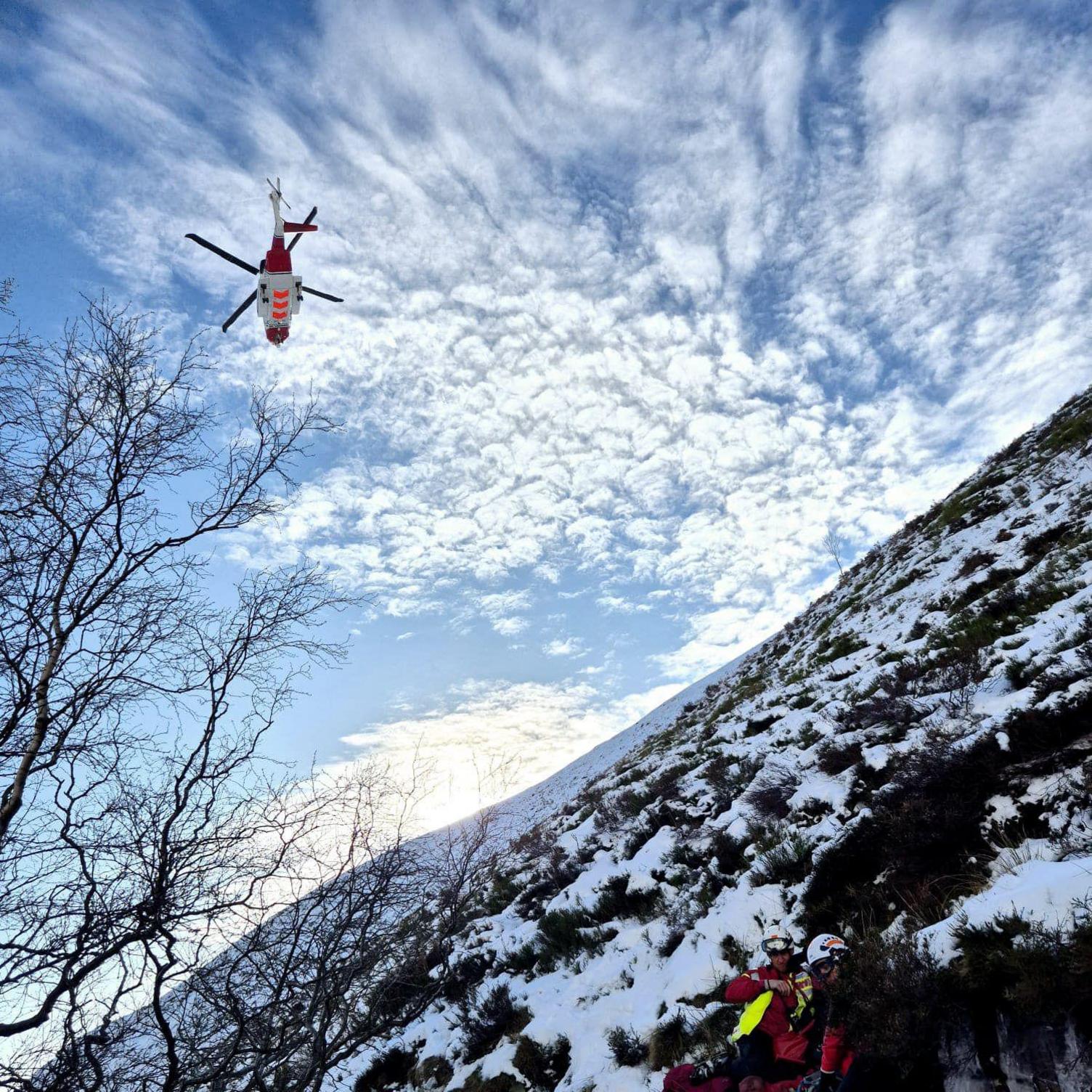 A hovering helicopter viewed from below on an icy slope