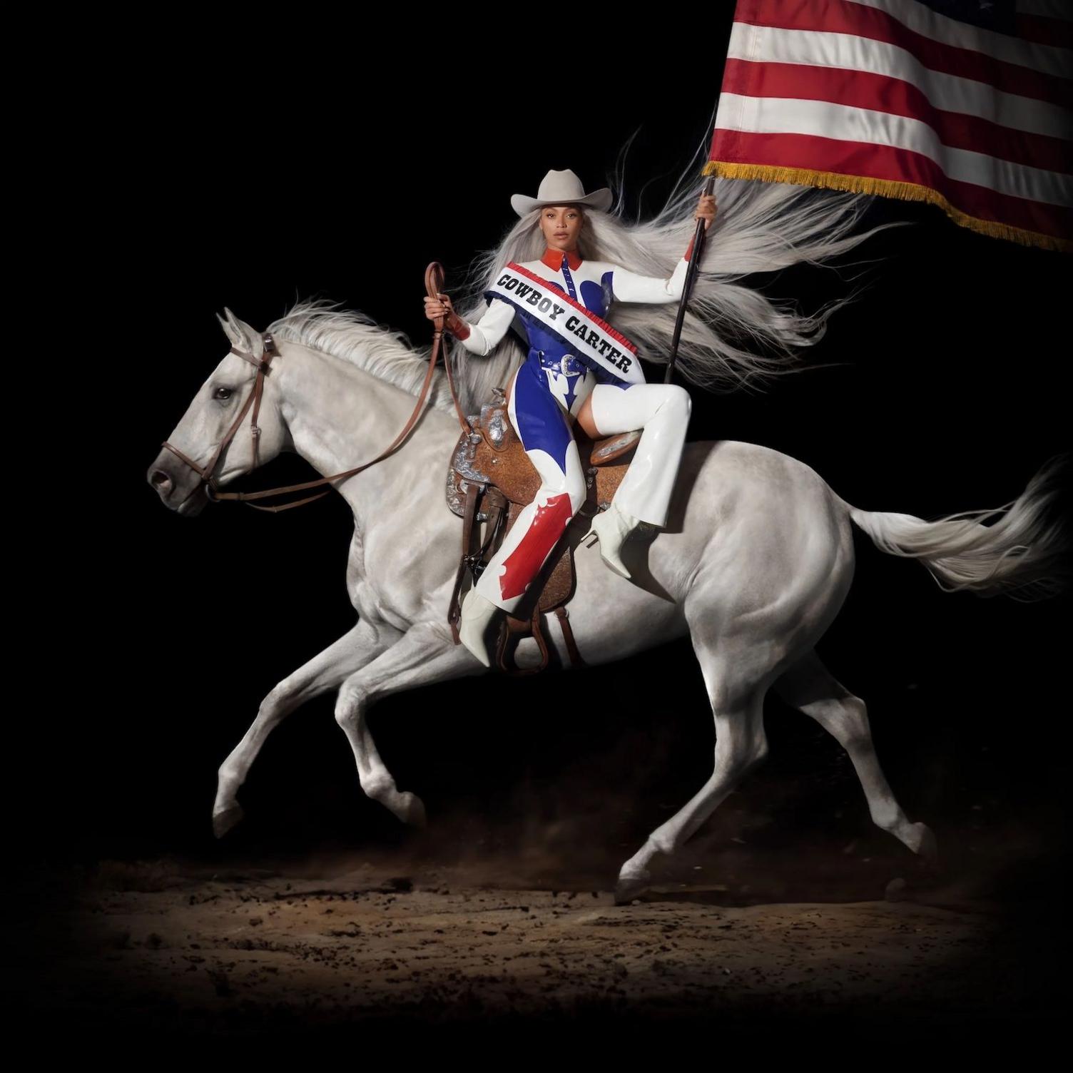 Artwork for Beyone's album Cowboy Carter. It shows Beyonce dressed in an Evil Knievel style outfit, a white cowboy hat waving the US flag while riding a white horse