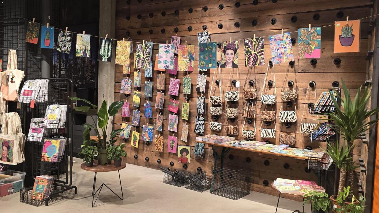 Different pieces of art work were hanging on a wooden wall on the left and across the room on a piece of string. On the right side of the wall were animal print bags hung on the wall.