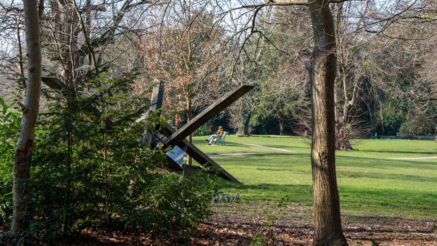 A woman can be seen sitting through a wooden art sculpture at South Hill Park Bracknell, England