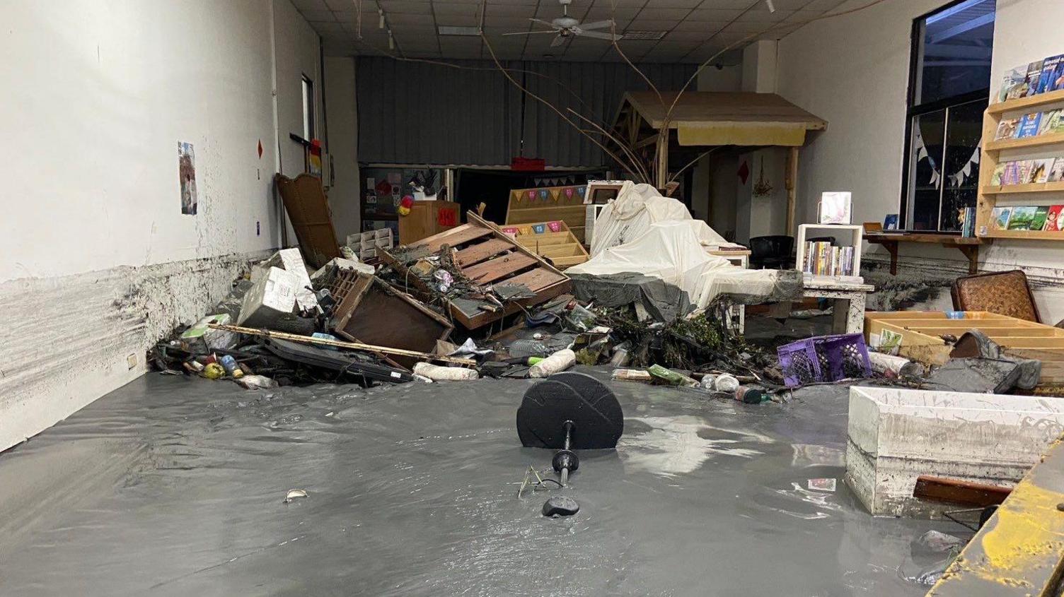 A bookshop drenched in mud, with a few collapsed bookshelves and other furniture