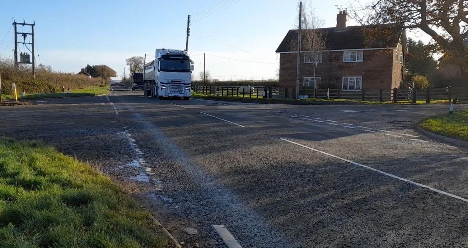 White HGV in the background travelling along a country road towards the camera