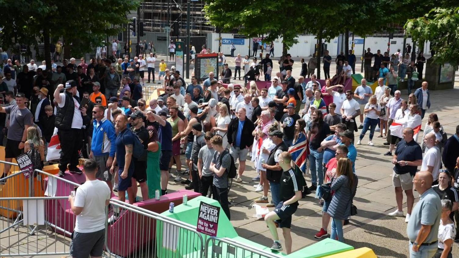 Dozens of people stand behind metal barriers during a far-right demonstration held on The Headrow in Leeds