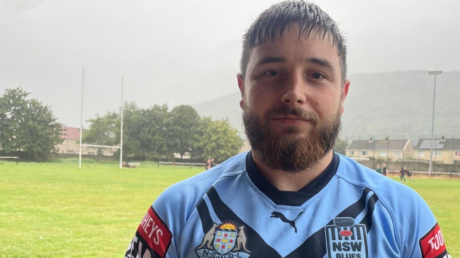 Rugby player Morgan Evans, in his playing kit, standing near a rugby field