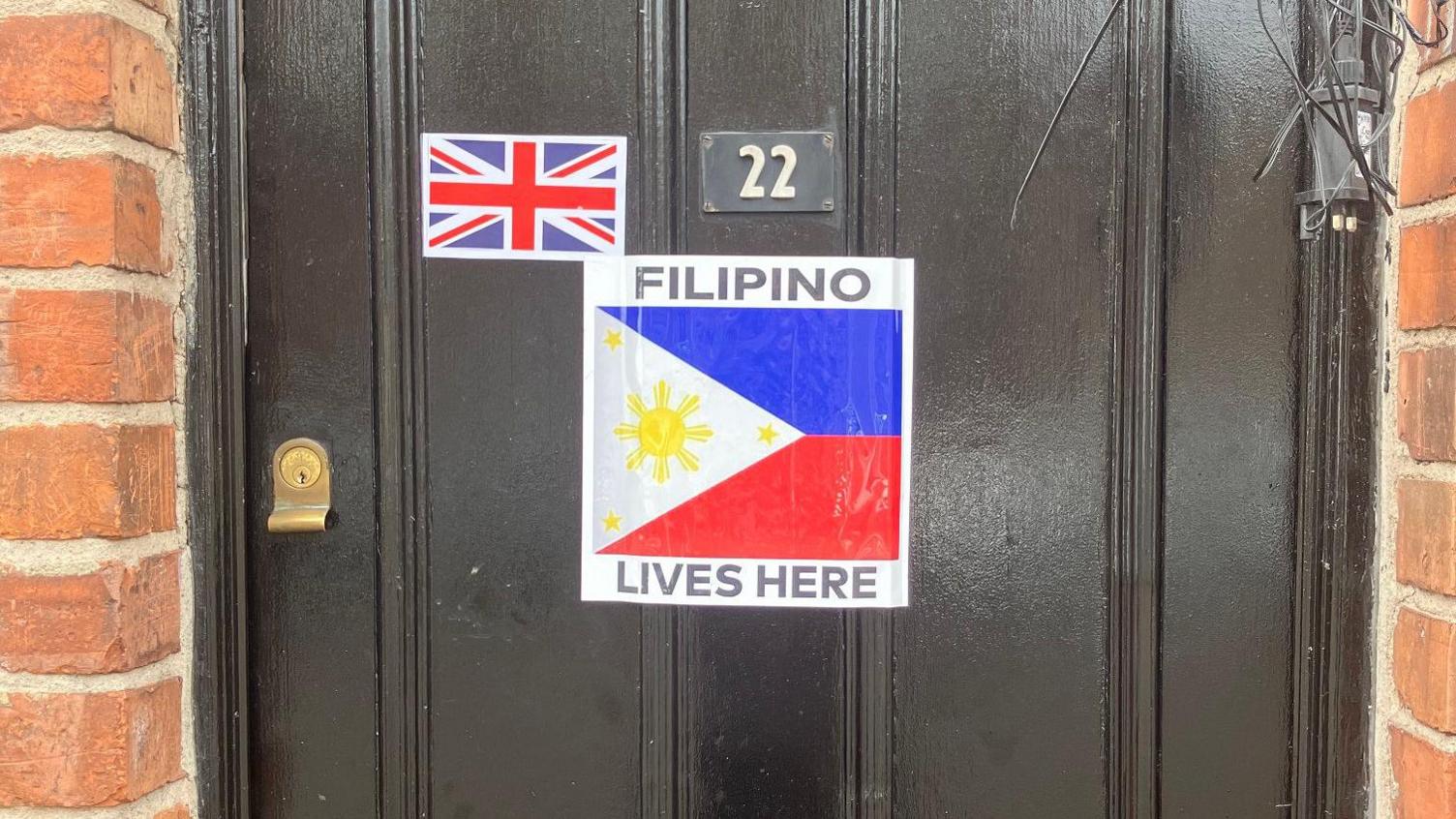 A black front door with a sticker saying Filipino lives here on it