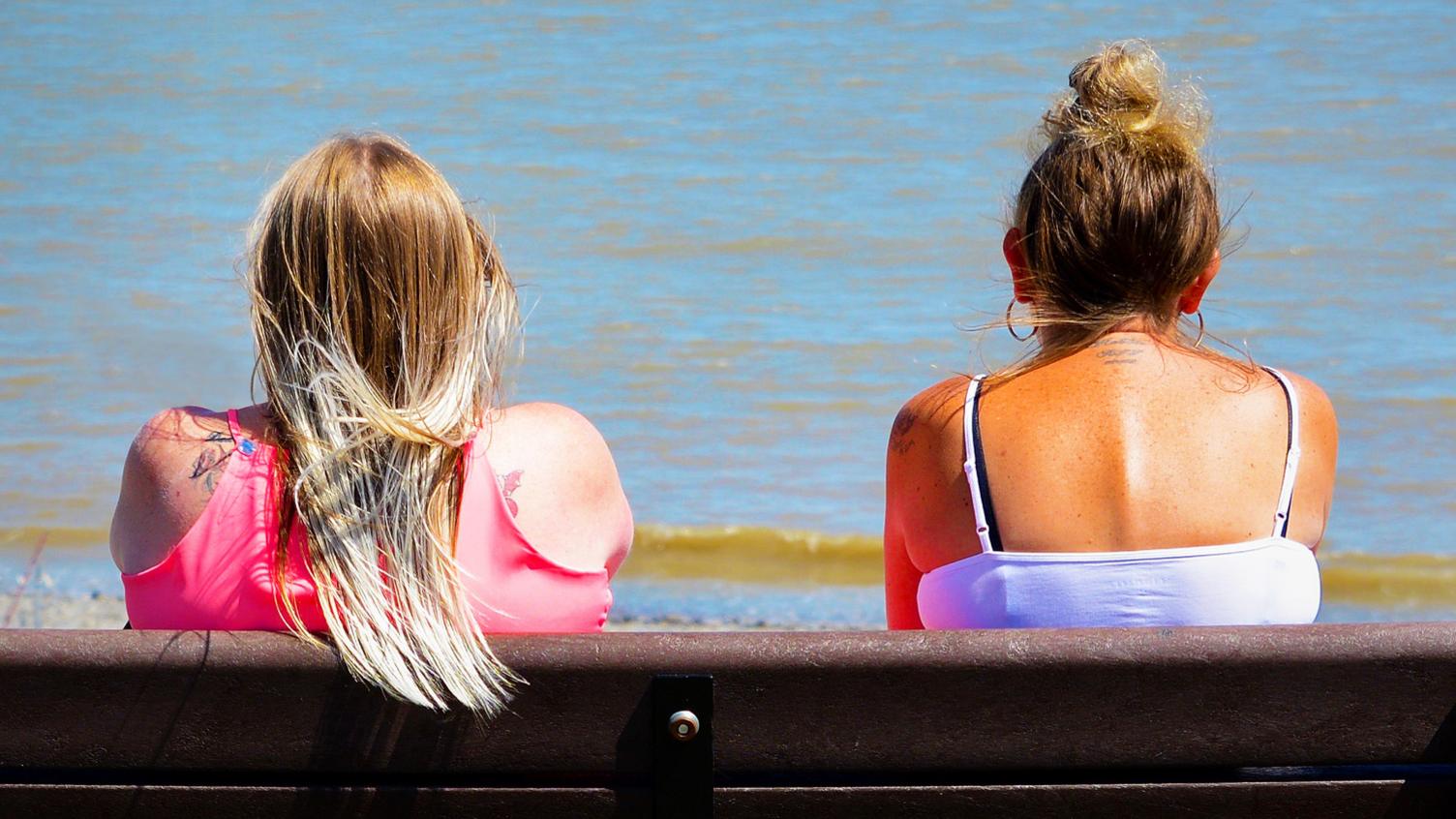 Two women on bench by the sea