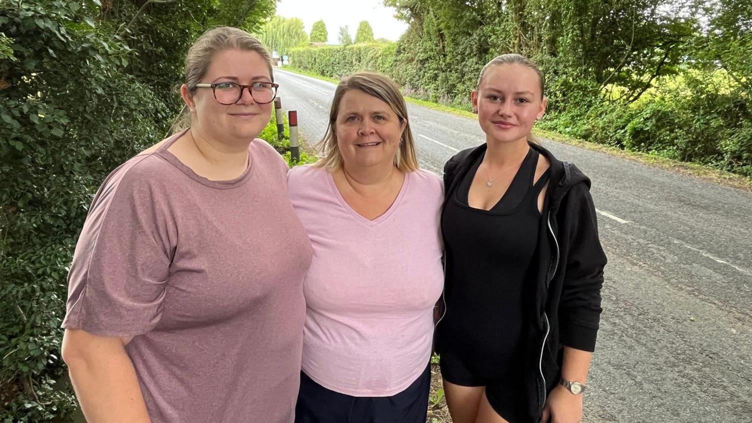 Three women standing by the side of a narrow road in Marden, a Kent village.