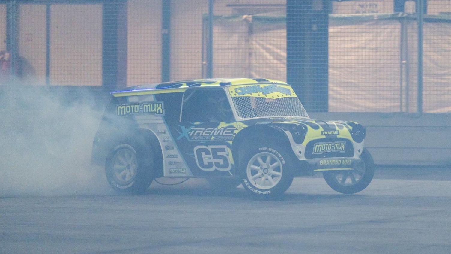 A car during the motorsport show can be seen smoking its tyres, with the image visibly hazy from the pollution.