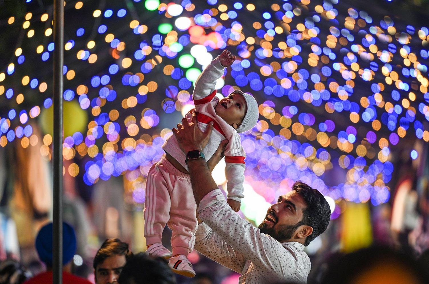 A man lifting up his child to see Diwali lightings set up at Janpath Market in New Delhi