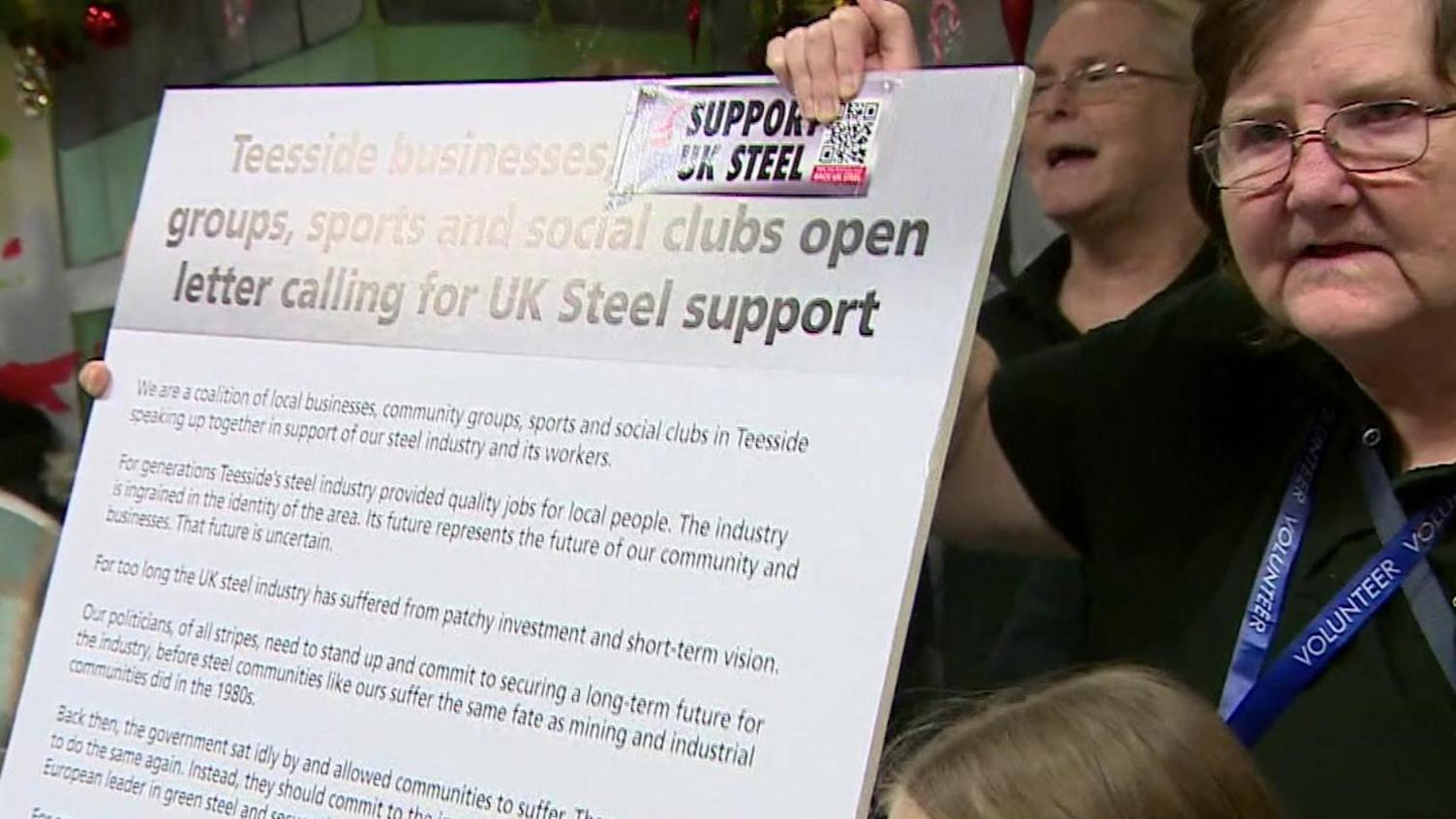 People holding up a board with an open letter calling for steel production on Teesside