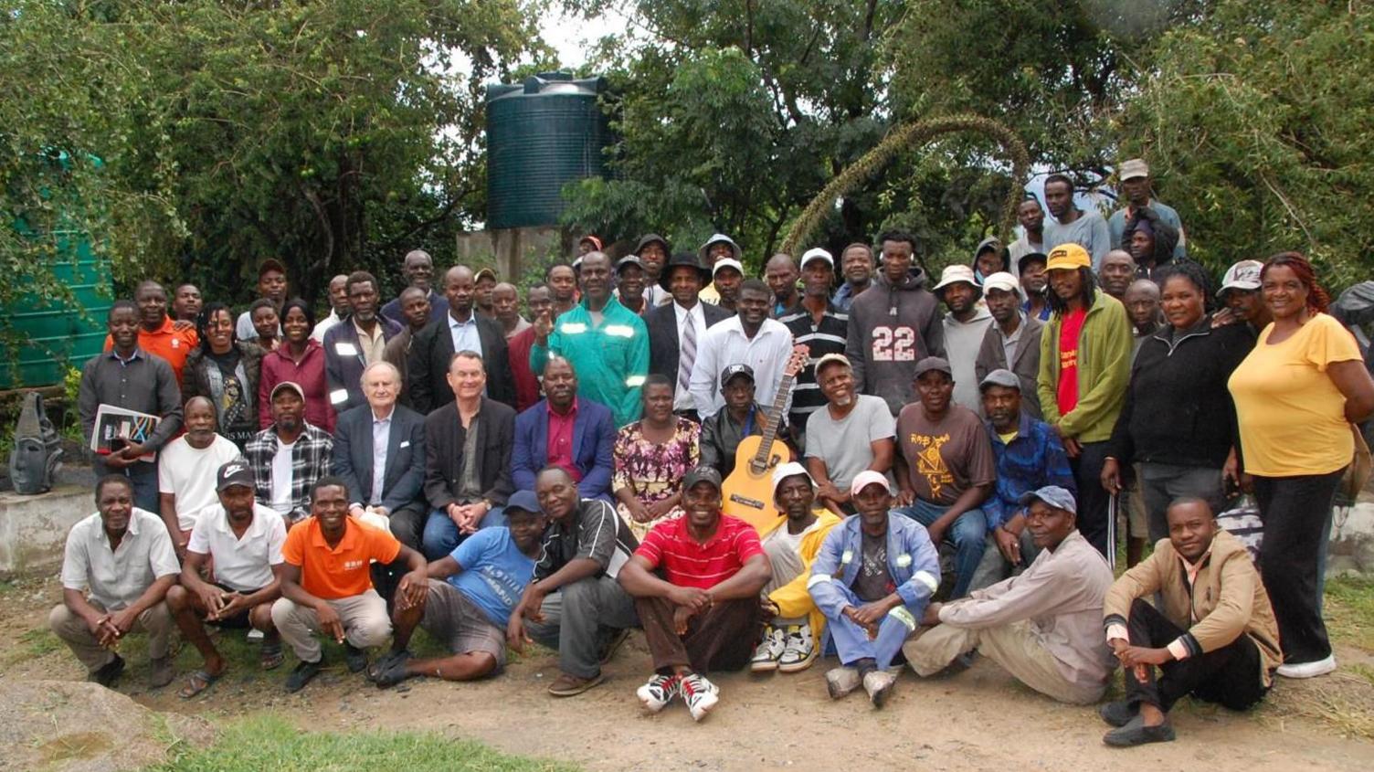 About 60 attendees at the launch of the competition outside the arts centre in Zimbabwe, posing for a group photo.  One man holds a guitar, another carries books.