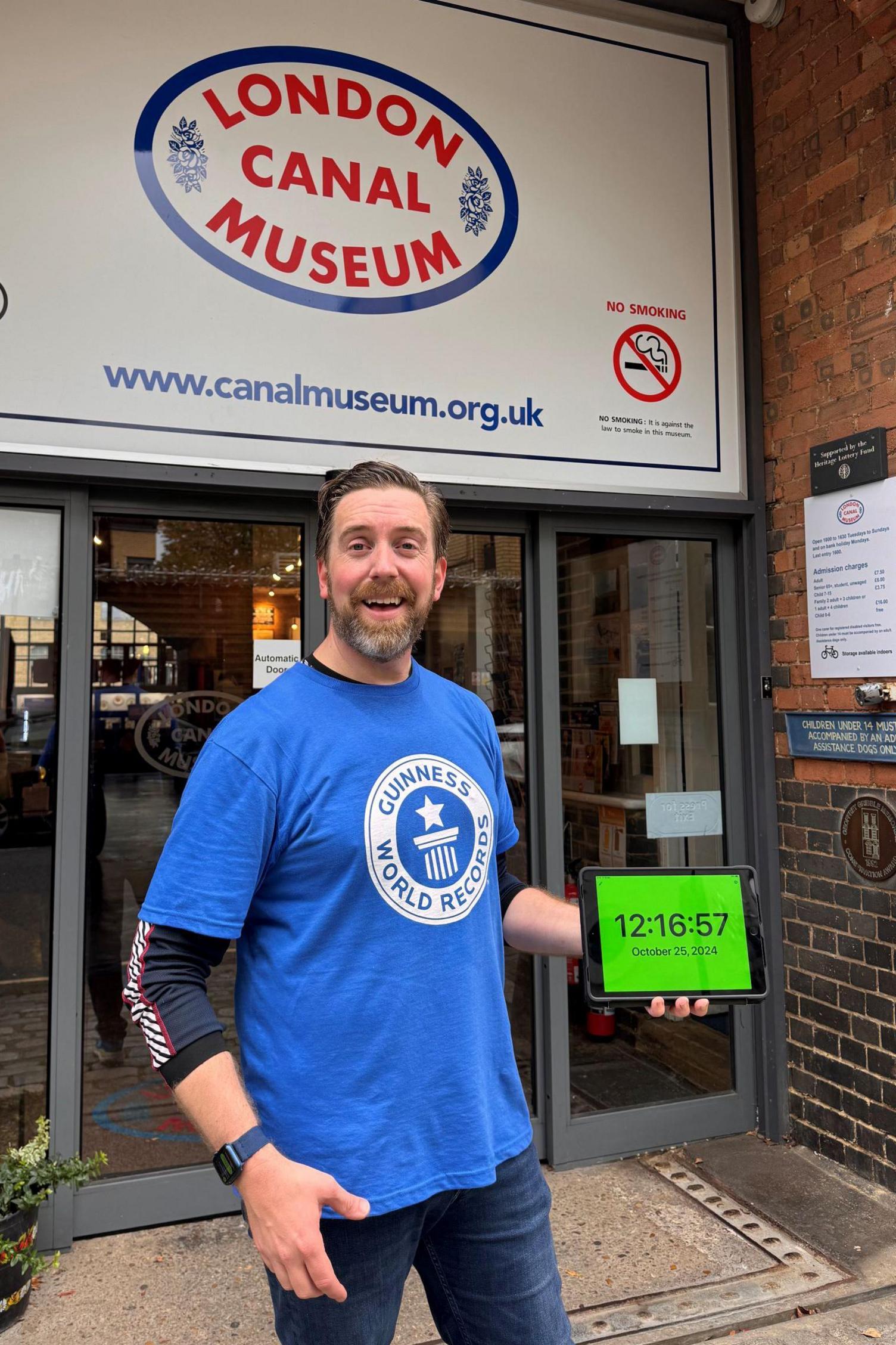 Ben Melham outside the canal museum. He is looking pleased and is holding a tablet with the timing on, as proof he has made the record.