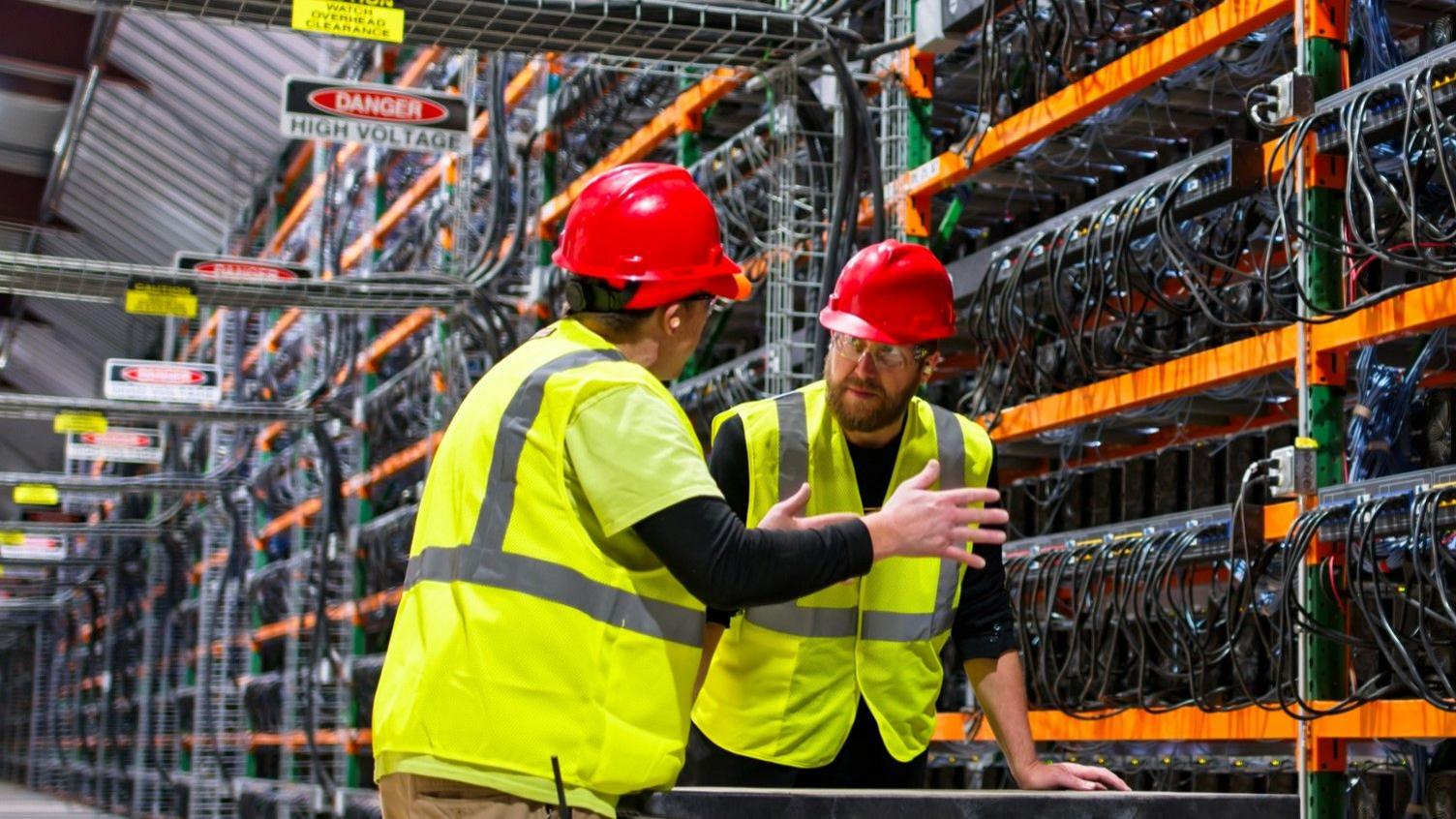 Two workers in a datacentre in hi-vis jackets