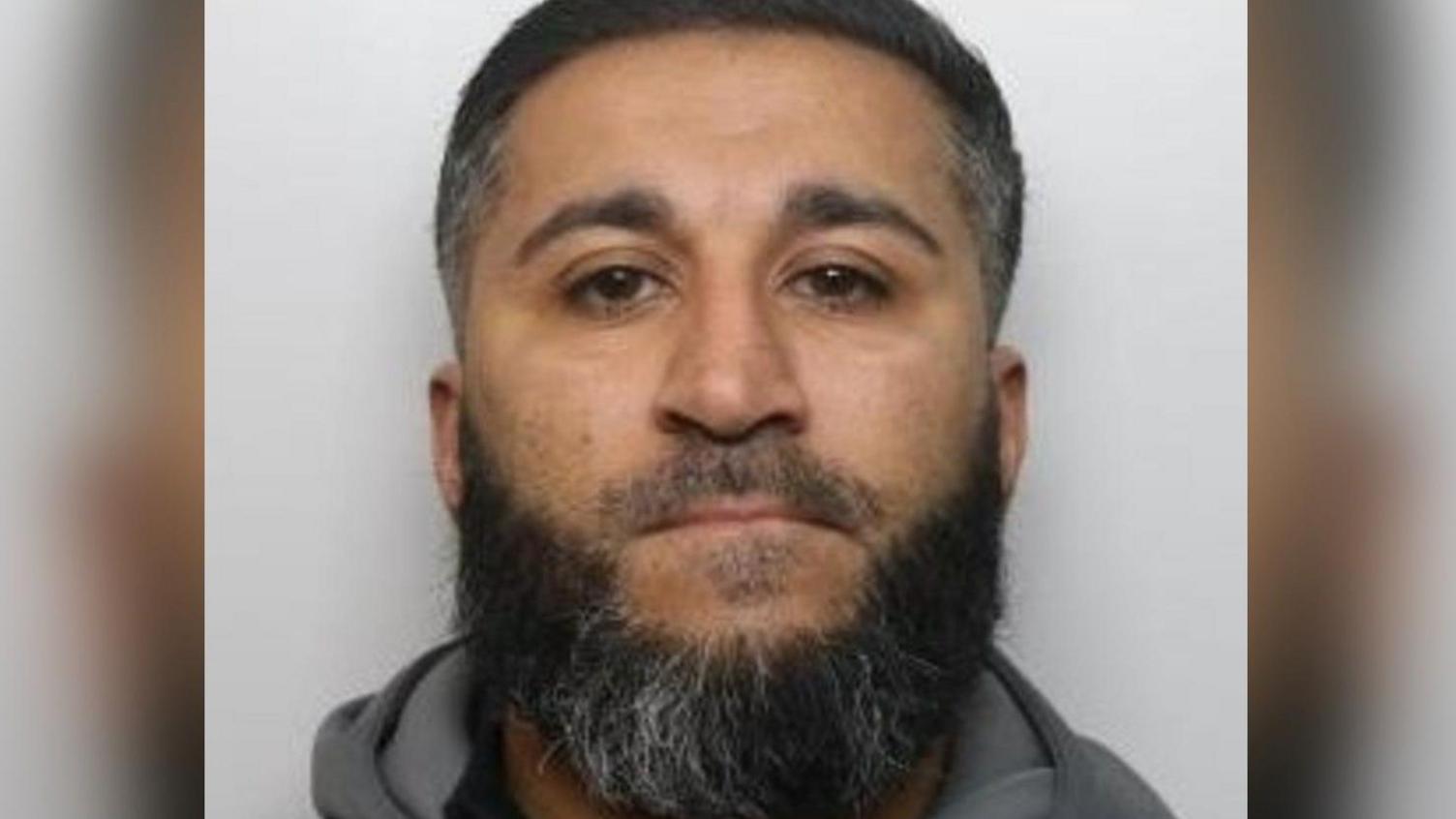 Mugshot of rapist Amar Khan, 42, who has black hair and a black and grey beard.