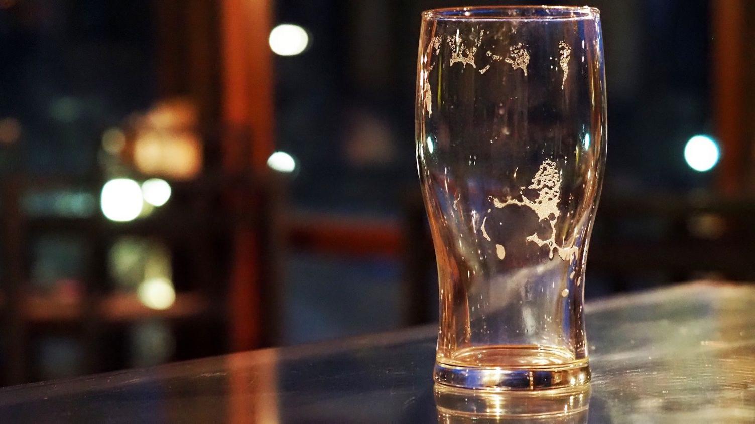 An empty pint glass in a pub