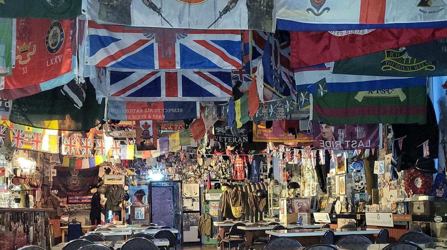 The inside of The Last Post which has flags covering the ceiling and memorabilia can be seen on the wall in the background. 