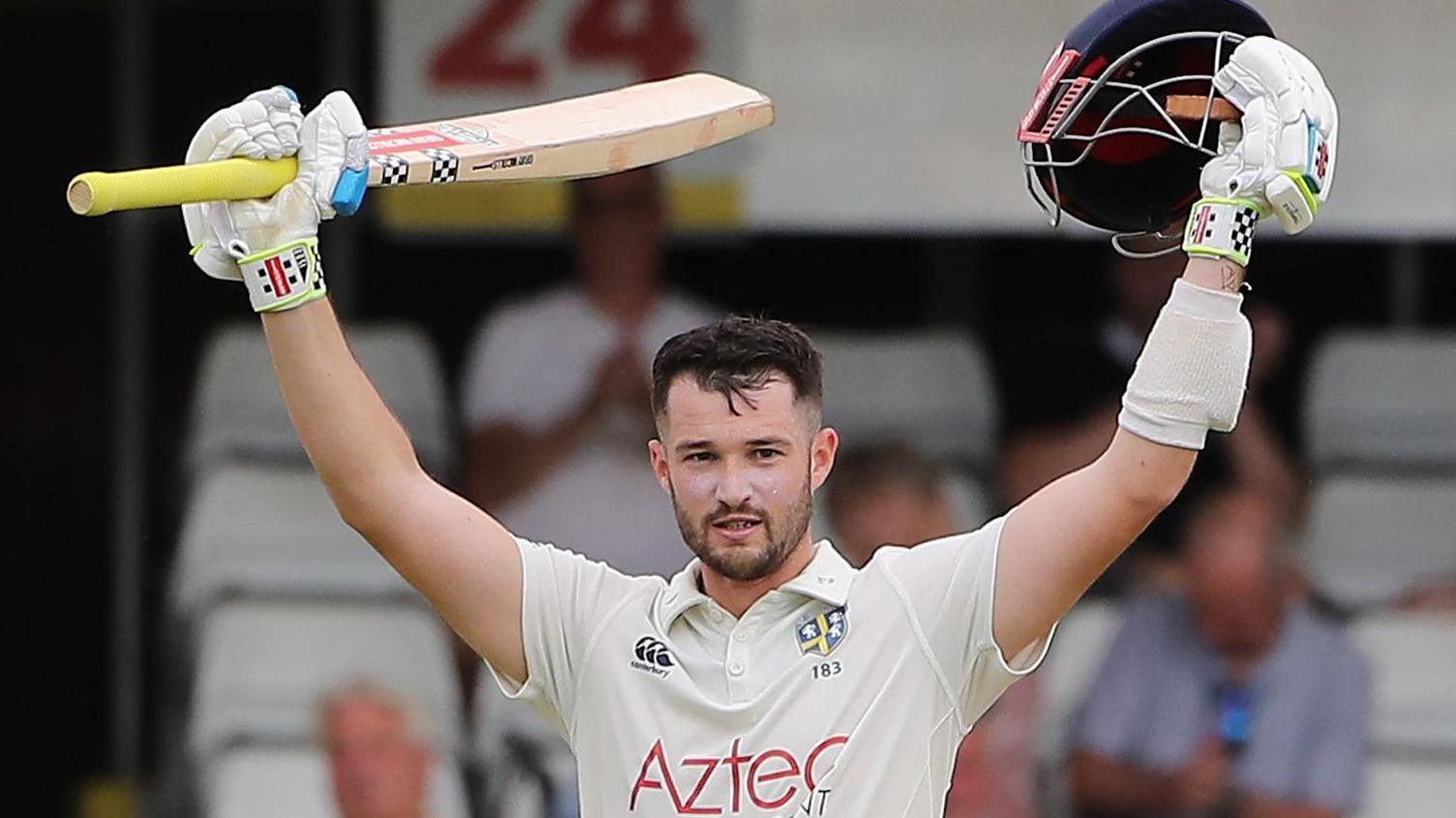 Ollie Robinson raises his bat after hitting a century for Durham against Essex