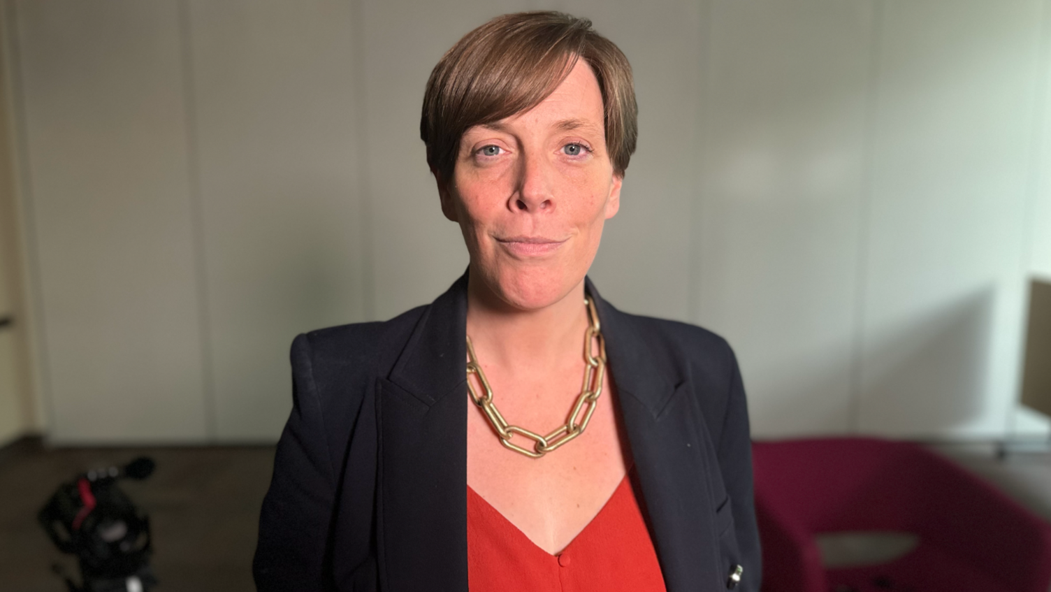 Safeguarding minister Jess Phillips MP wearing a black blazer, red top and gold chain, smiling at the camera