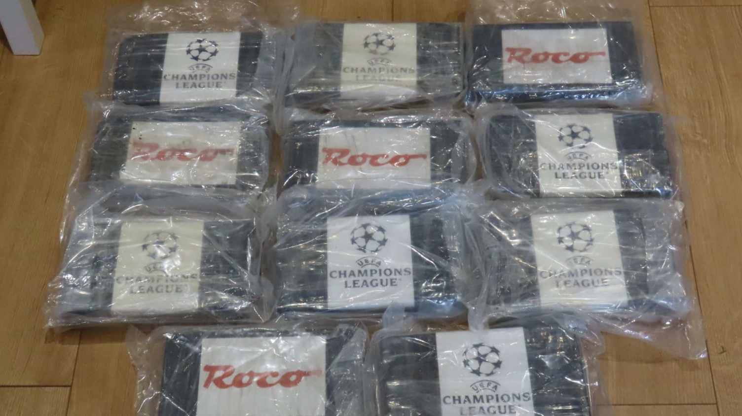 A selection of drugs wrapped in plastic with labels on which say 'Champions League' and Roco. They are laid out on a wooden floor