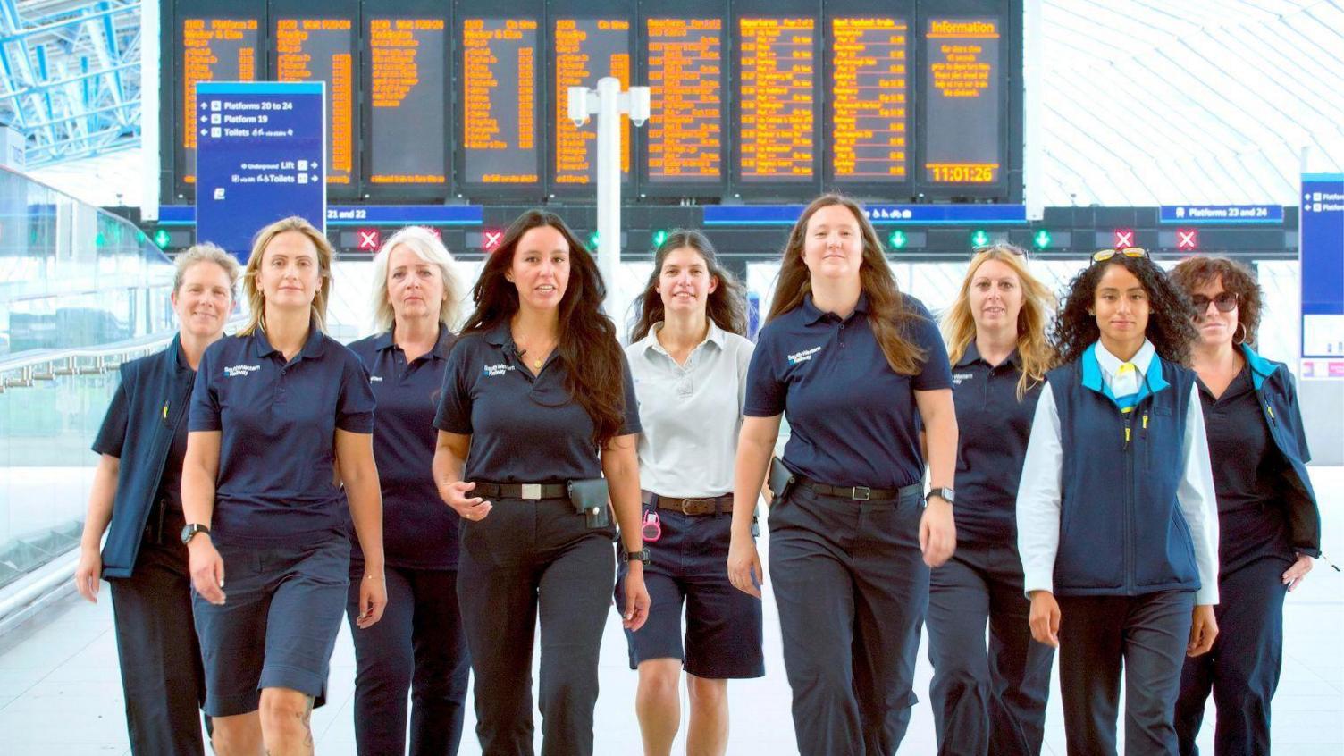 A group of women train drivers from South Western Railway walking at a train station