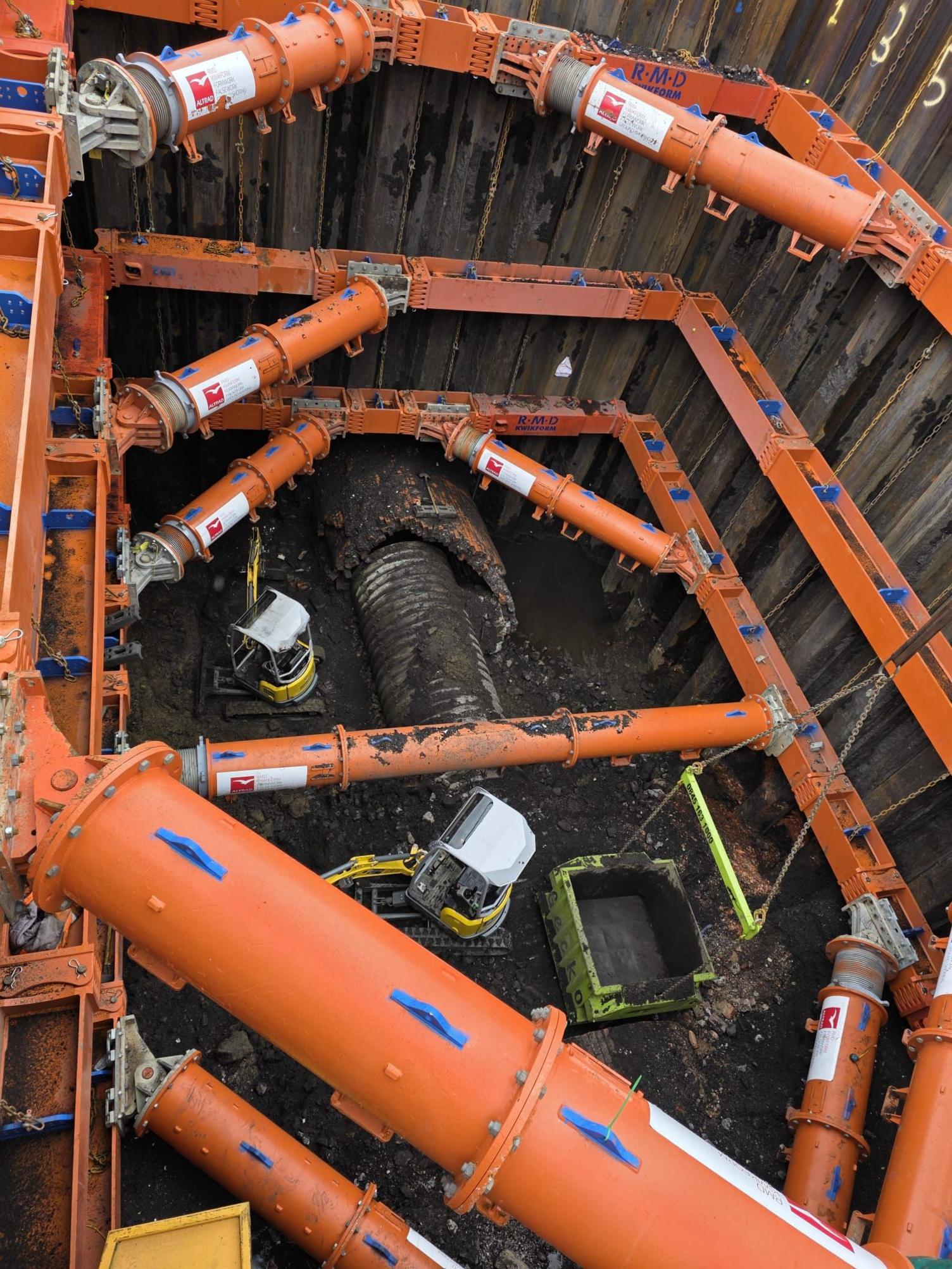 Inside the sinkhole - there are orange pipes that are trying to stabilise the hole. There is machinery at the bottom. 