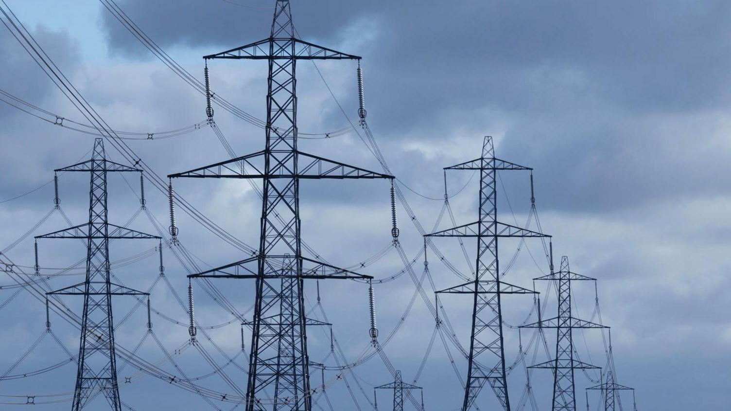Six pylons standing against a gloomy, grey sky.